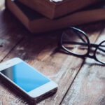 Phone, books, & glasses on wooden tabletop