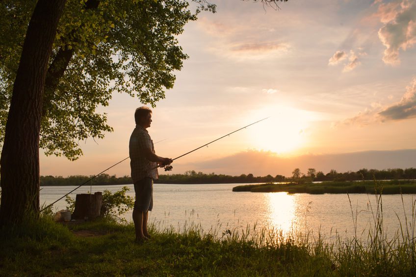 fisherman with a fishing man fishing during sunset